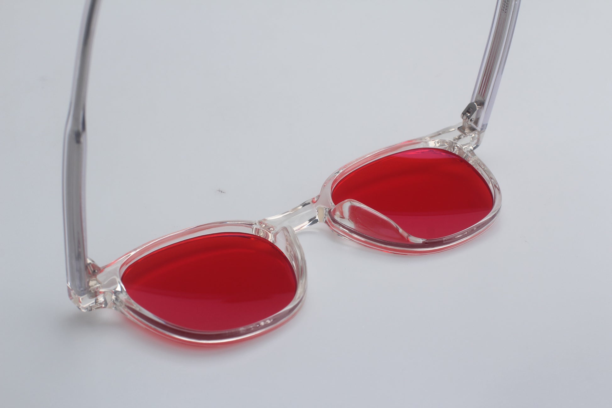 Blue Light blocking glasses (blålysbriller) with red lenses and clear frame on a light gray background