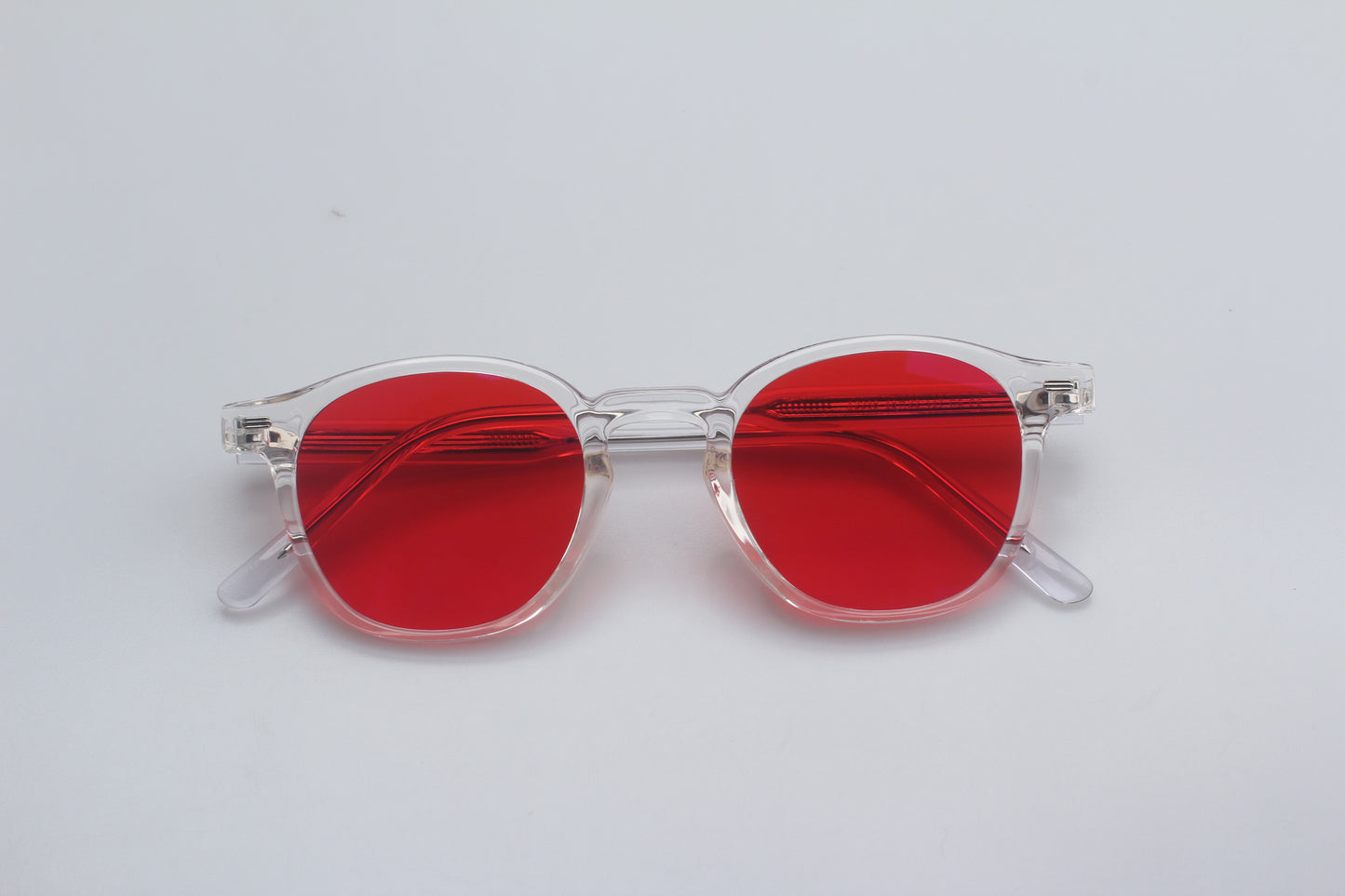 Blue Light blocking glasses (blålysbriller) with red lenses and clear frames on a light gray background