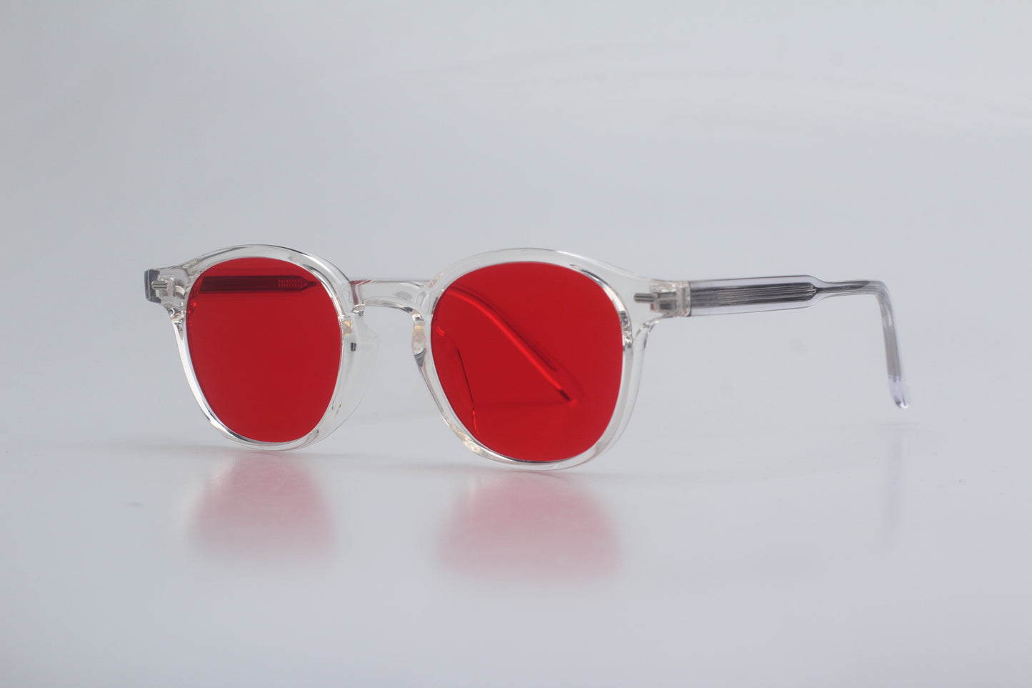 Blue Light blocking glasses (blålysbriller) with red lenses and clear frame on a light gray background