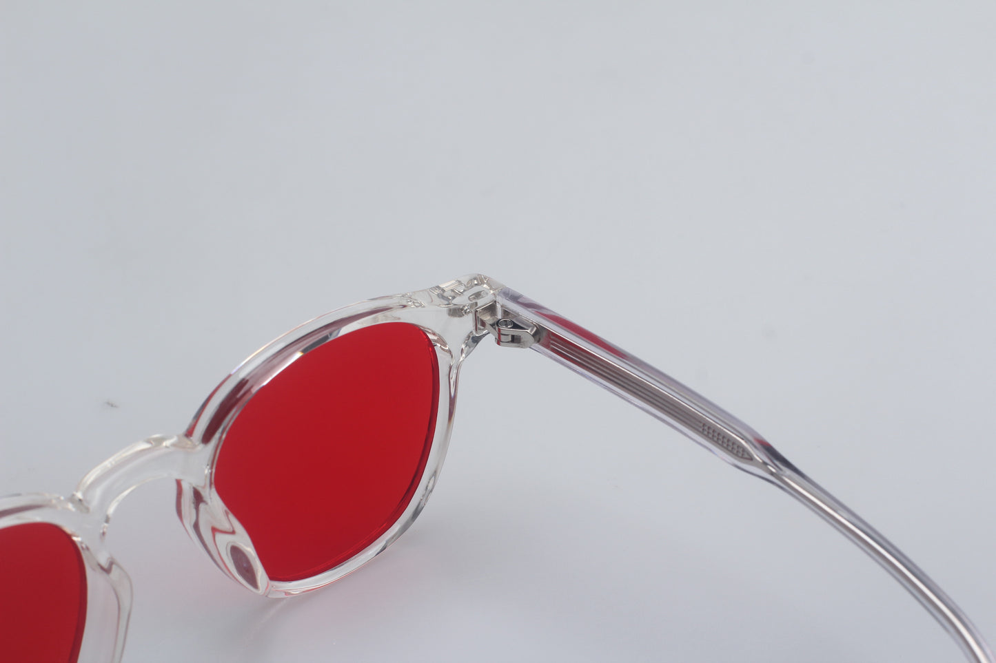 Blue Light blocking glasses (blålysbriller) with red lenses and clear frame on a light gray background