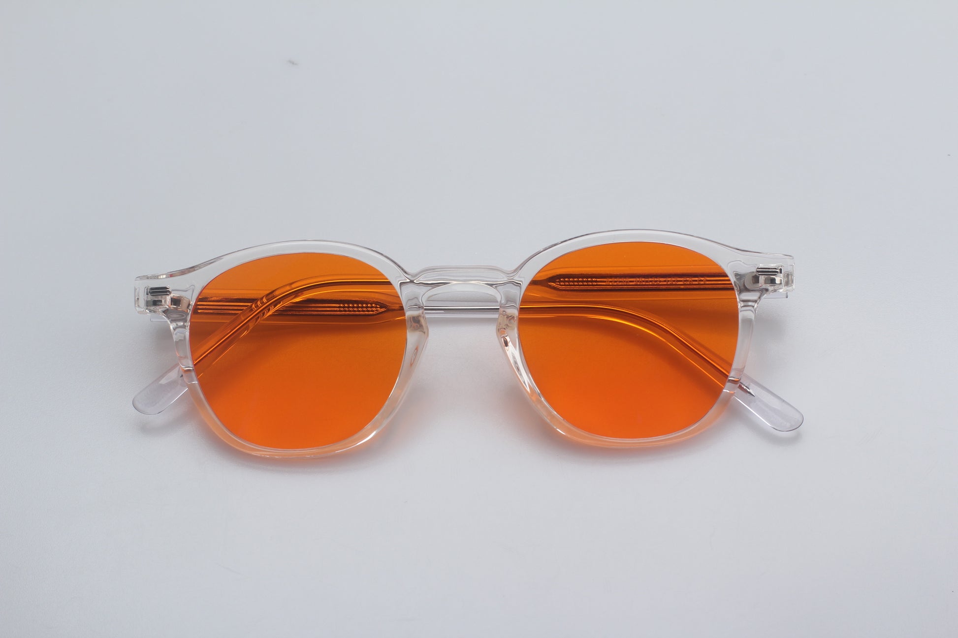 Blue Light blocking glasses (blålysbriller) with orange lenses and clear frame on a white background