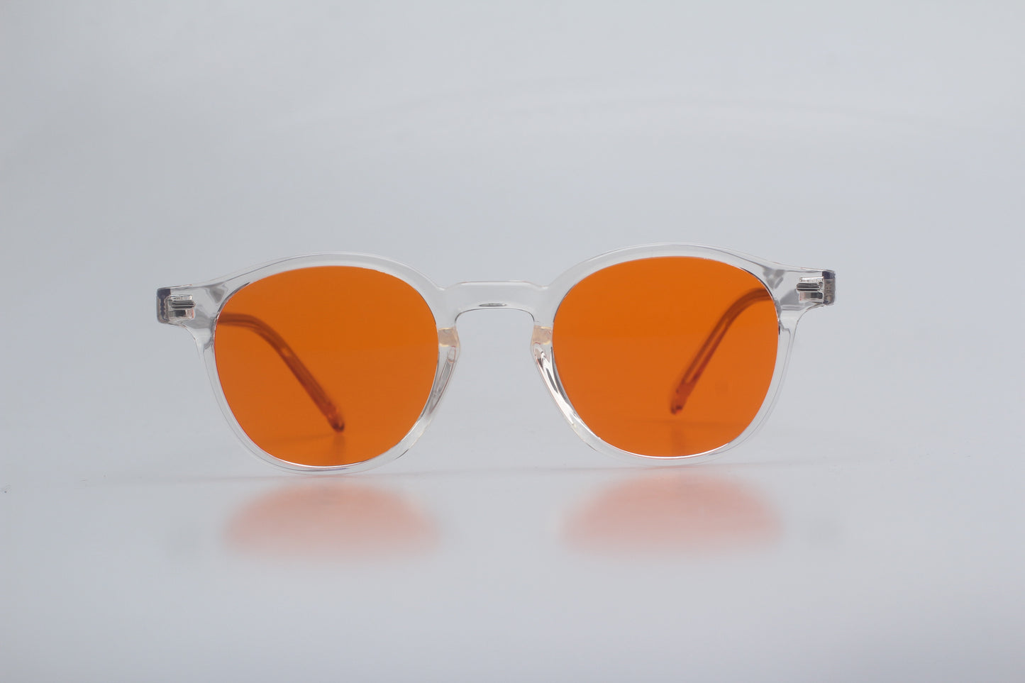 Blue Light blocking glasses (blålysbriller)with orange lenses and clear frames on a light gray background
