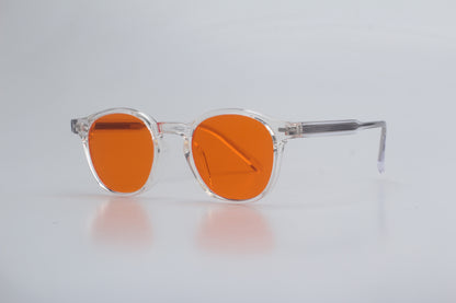 Blue Light blocking glasses (blålysbriller) with orange lenses and clear frames on a light gray background