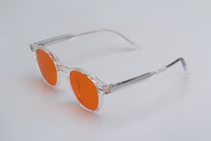 Blue Light blocking glasses (blålysbriller) with orange lenses and clear frame on a light gray background