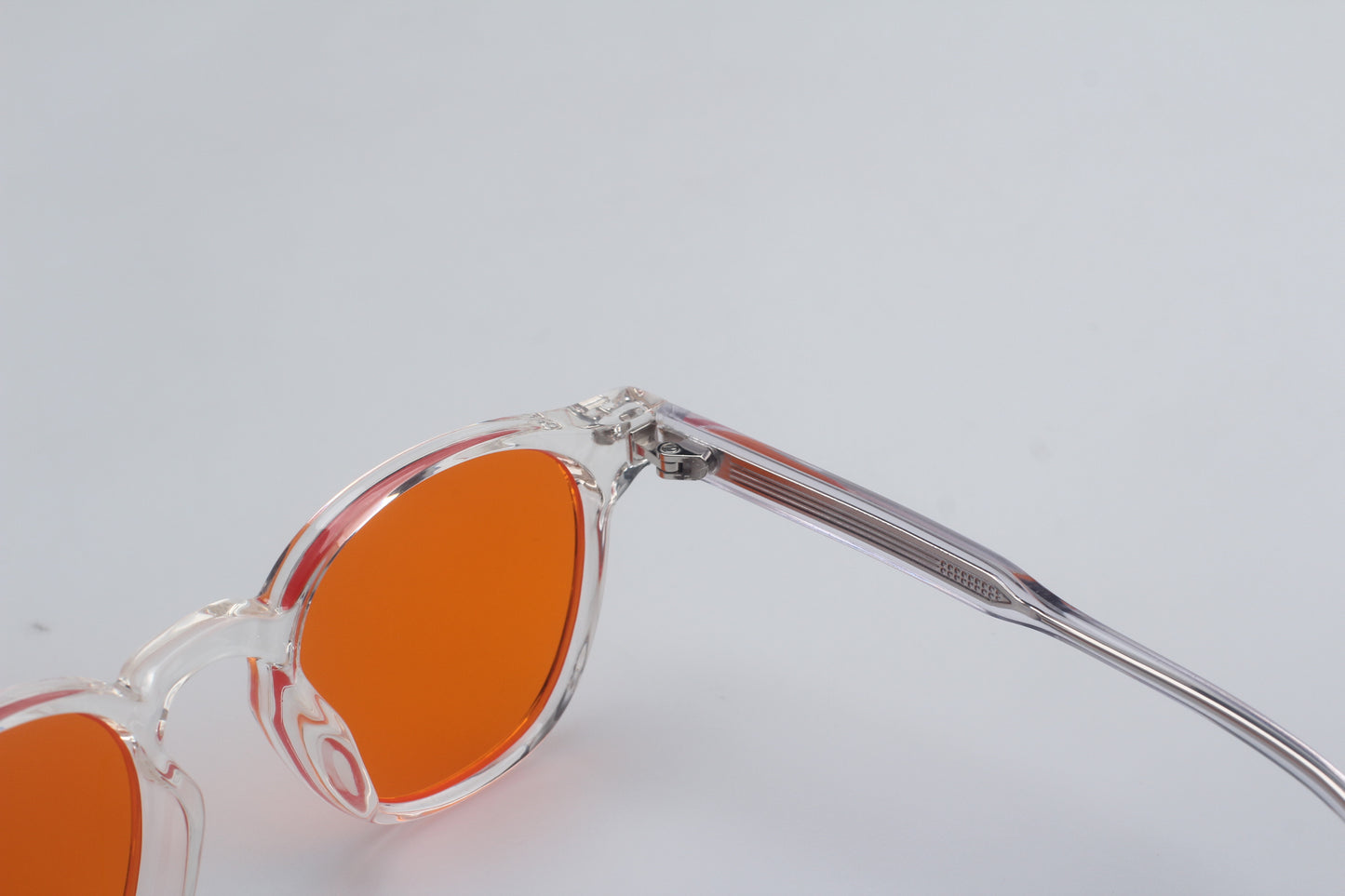Blue Light blocking glasses (blålysbriller) with orange lenses and clear frame on a light gray background
