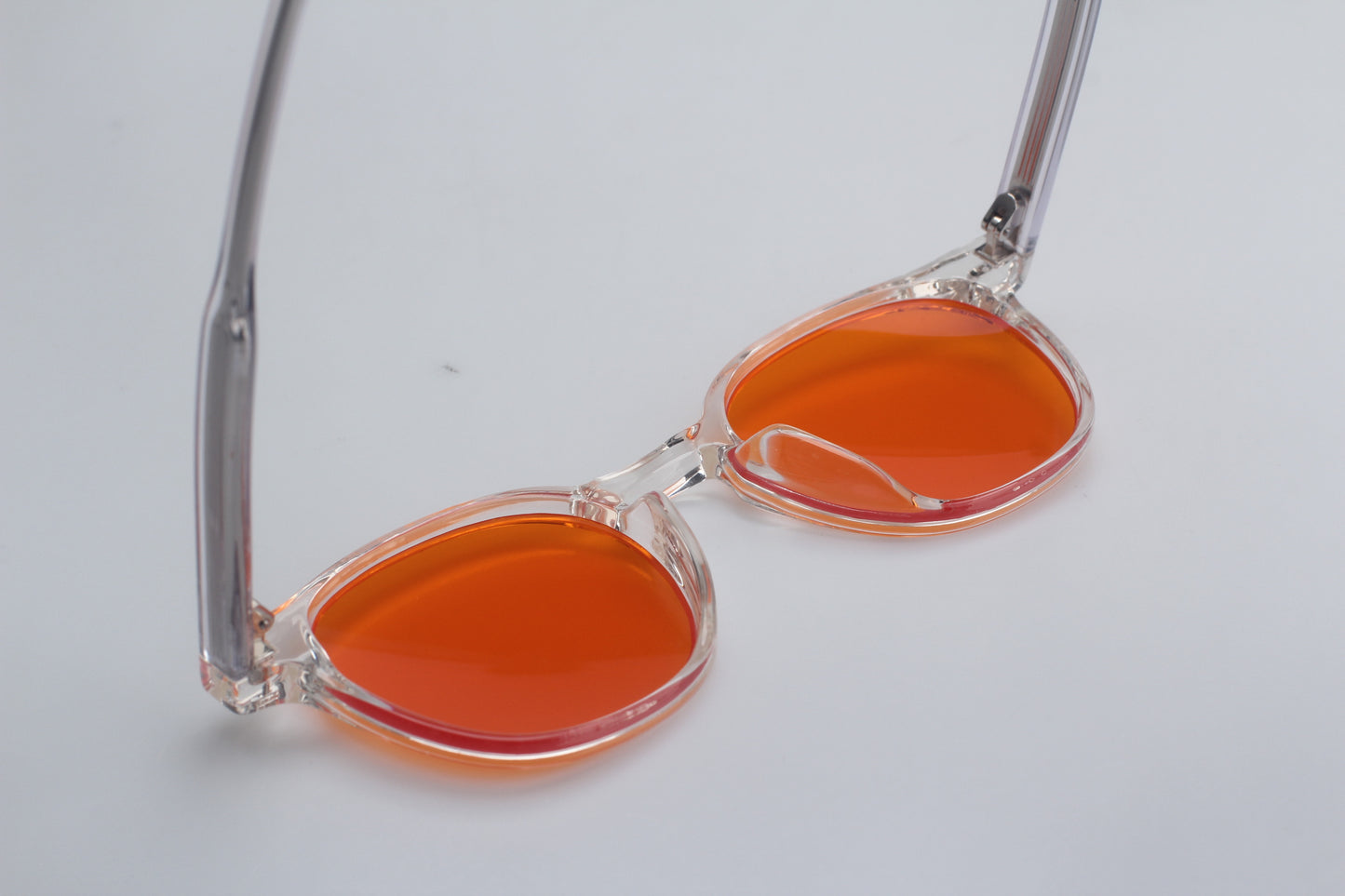 Blue Light blocking glasses (blålysbriller) with orange lenses and clear frames on a light gray background