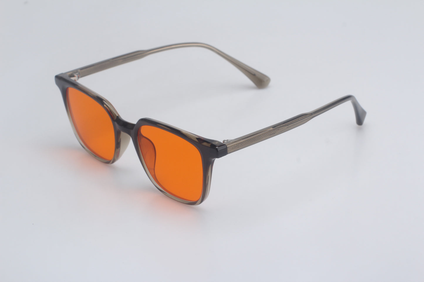 Blue light blocking glasses with orange lenses and black frames on a light gray background