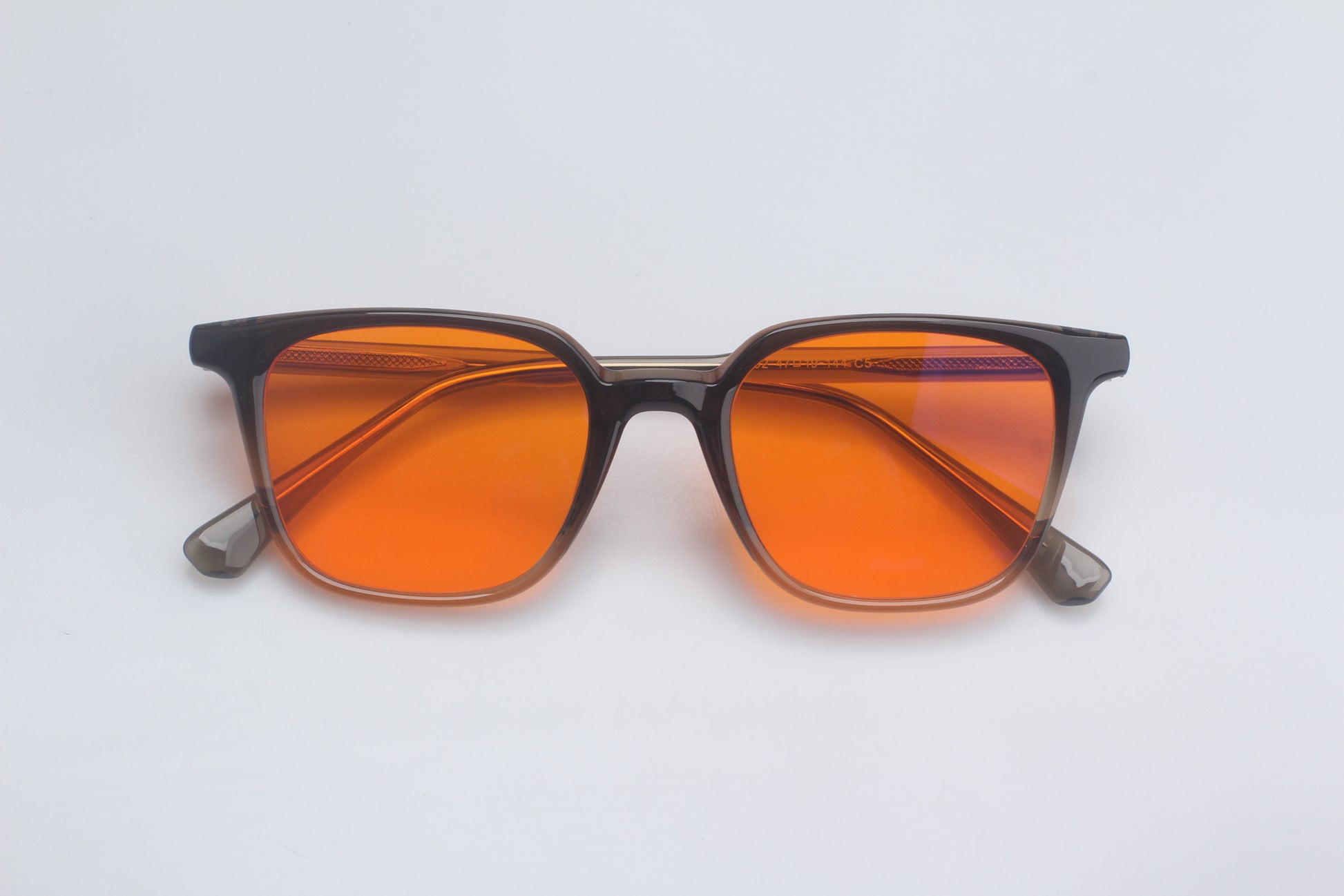 Blue Light blocking glasses with orange lenses and black frames on a white background