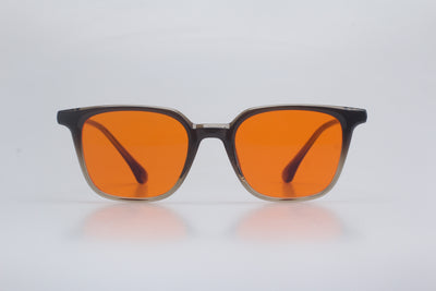 Blue light blocking glasses with orange lenses on a light gray background