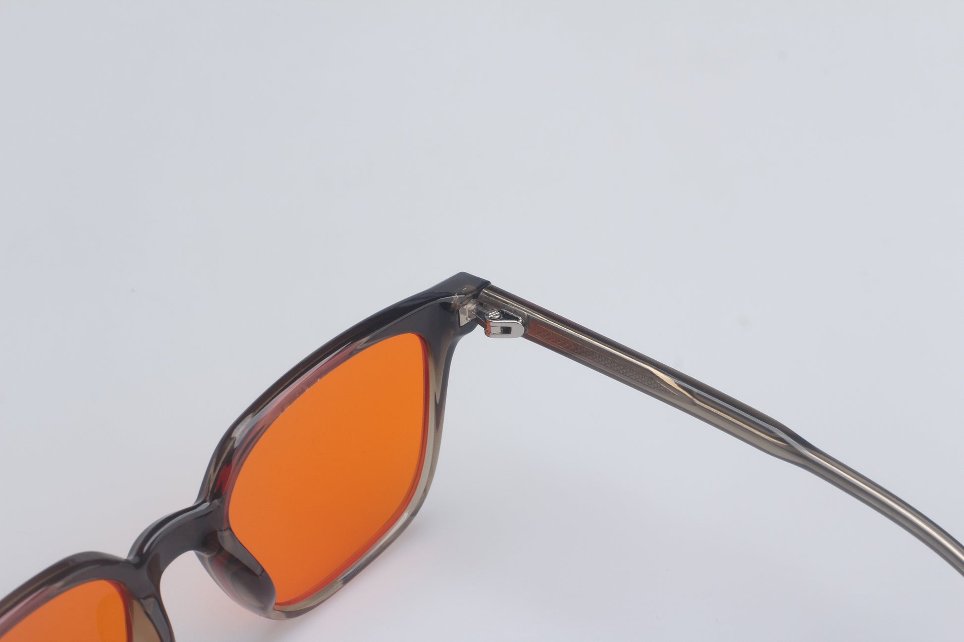 Blue light blocking glasses with orange lenses and dark frames on a light gray background