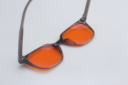 Blue Light blocking glasses with orange lenses and black frames on a light gray background