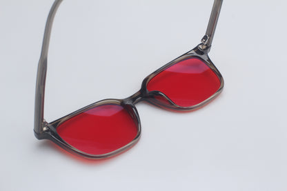 Blue light blocking glasses with red lenses and black frames on a light gray background