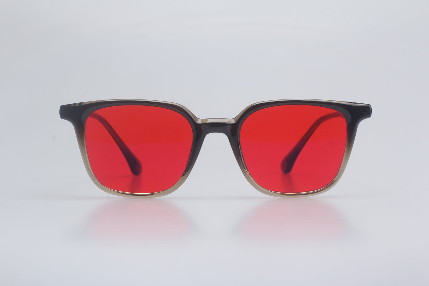 Blue light blocking glasses with red lenses and black frames on a light gray background