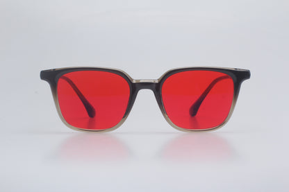 Blue light blocking glasses with red lenses and black frames on a light gray background