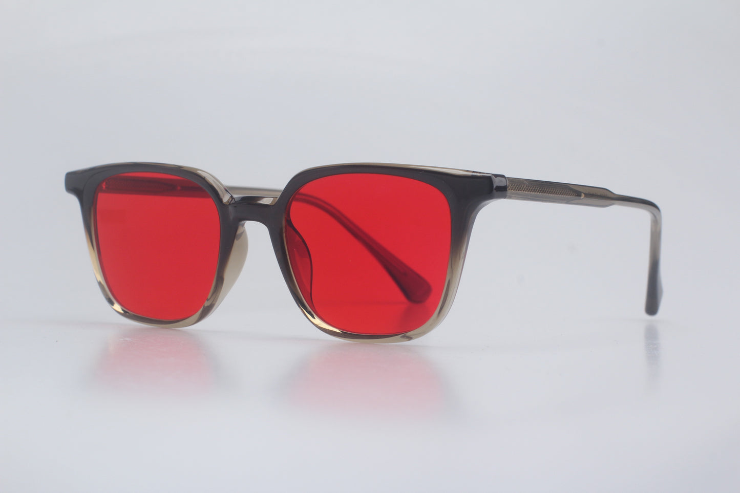Blue light blocking glasses with red lenses and dark frames on a light gray background