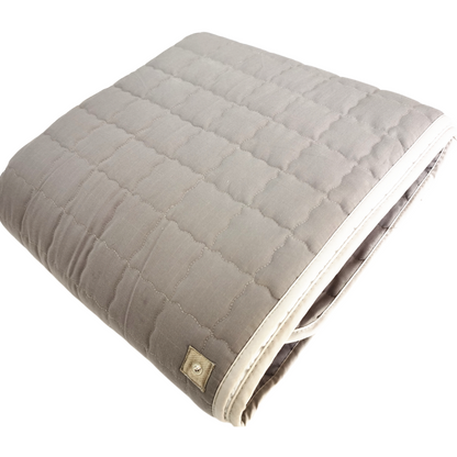 Quilted grounding blanket with a button closure on a white background