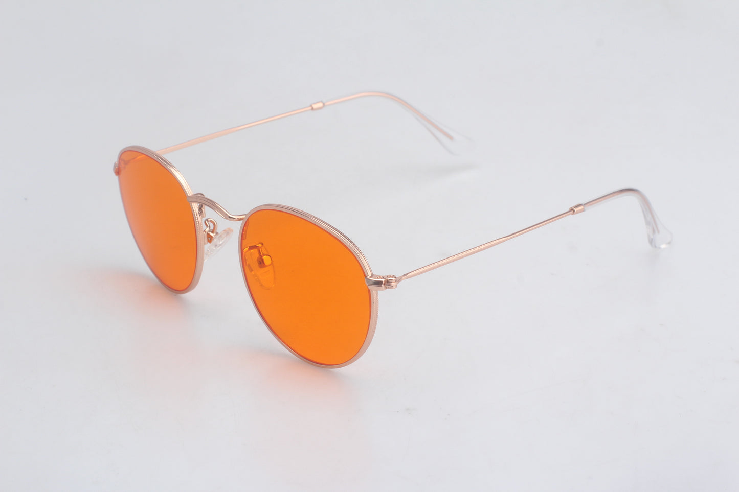 Blue Light blocking glasses with orange lenses and gold frames on a light gray background