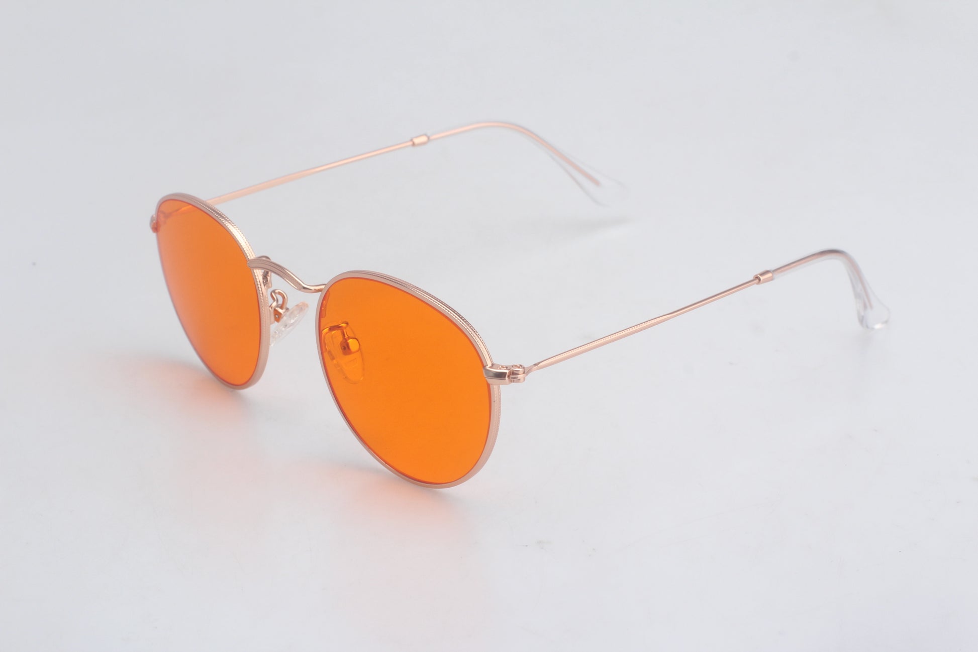 Blue Light blocking glasses with orange lenses and gold frames on a light gray background