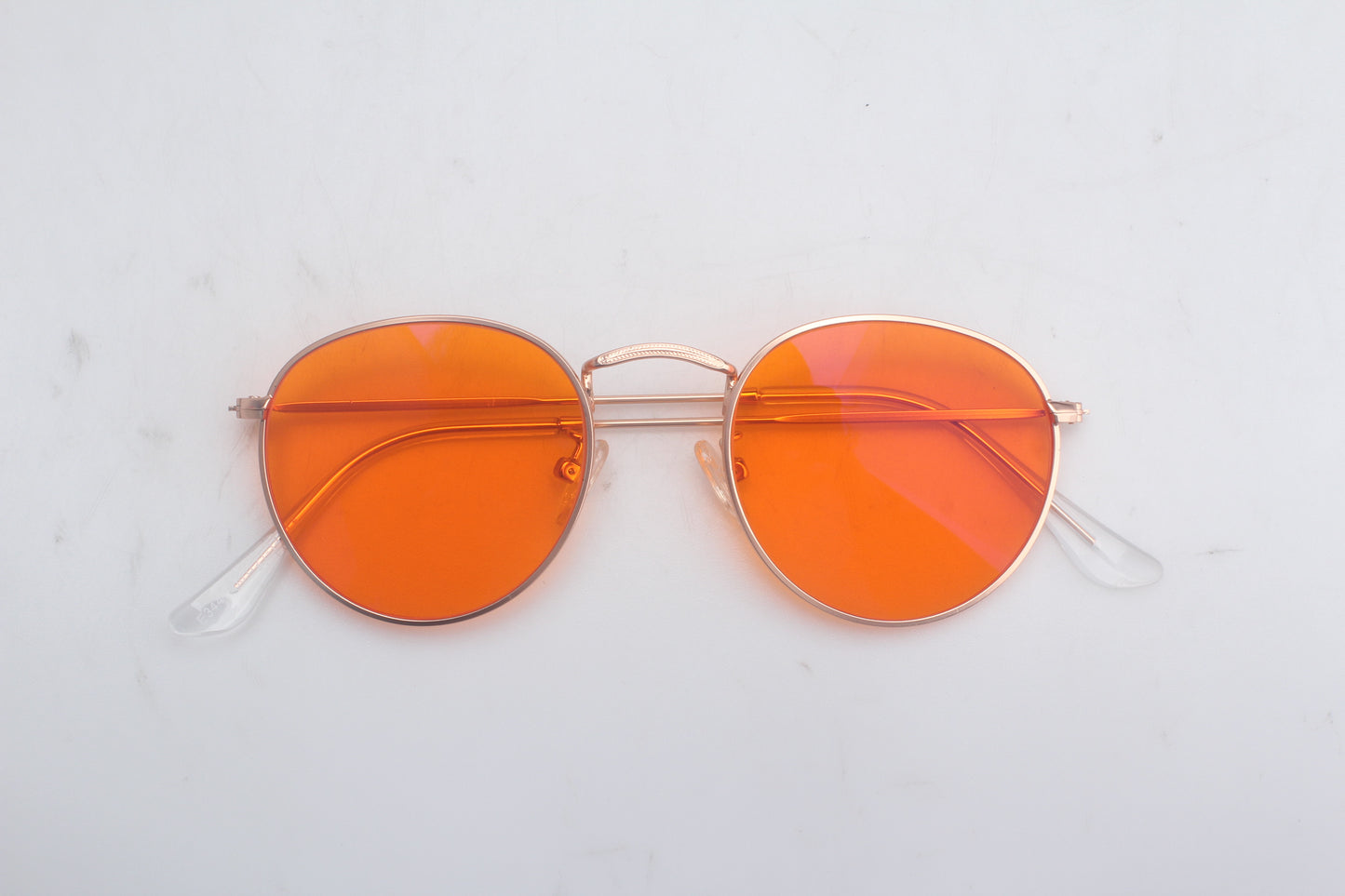 Blue light blocking glasses with orange lenses and gold frames on a light gray background