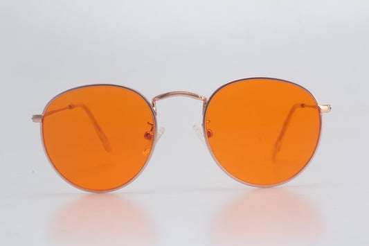 Round orange glasses with gold frame on a light gray background