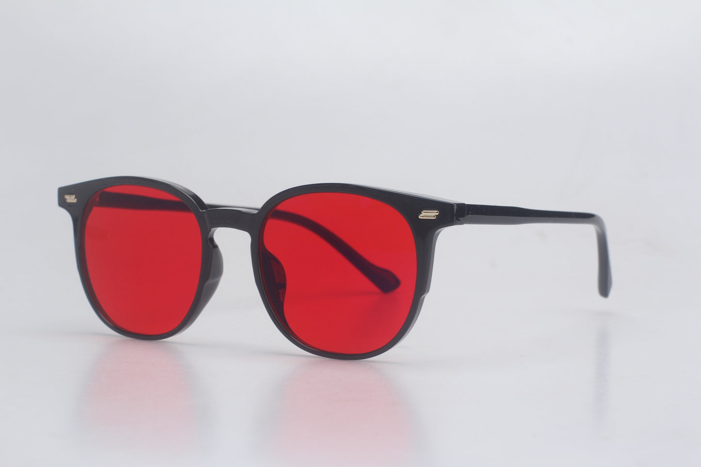 Blue Light blocking glasses with red lenses and black frames on a light gray background