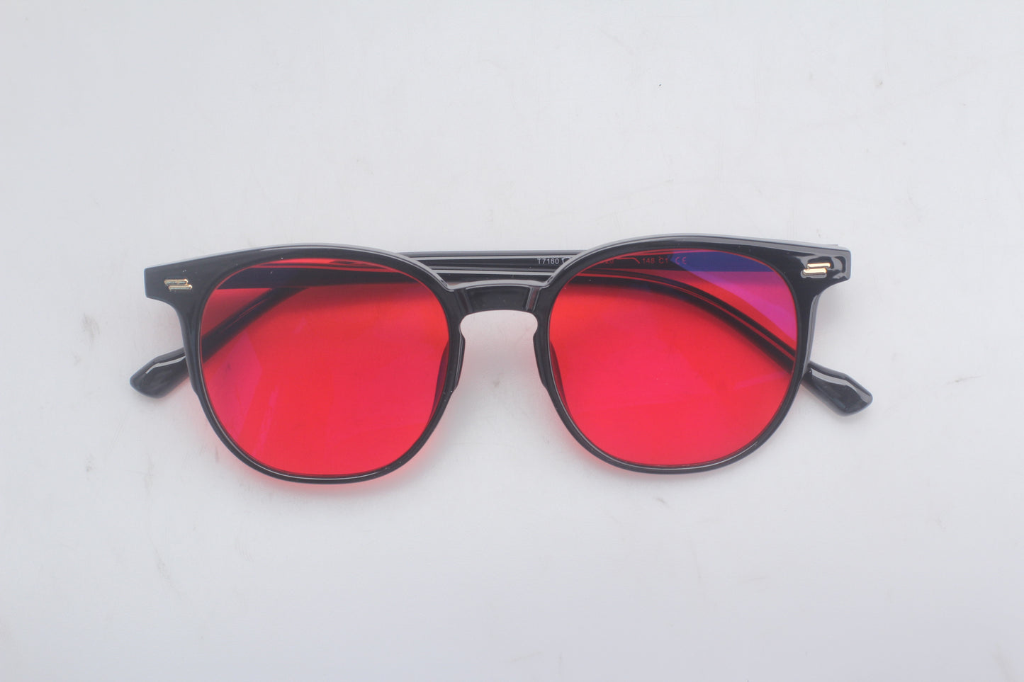 Blue light blocking glasses with red lenses and black frames on a white background