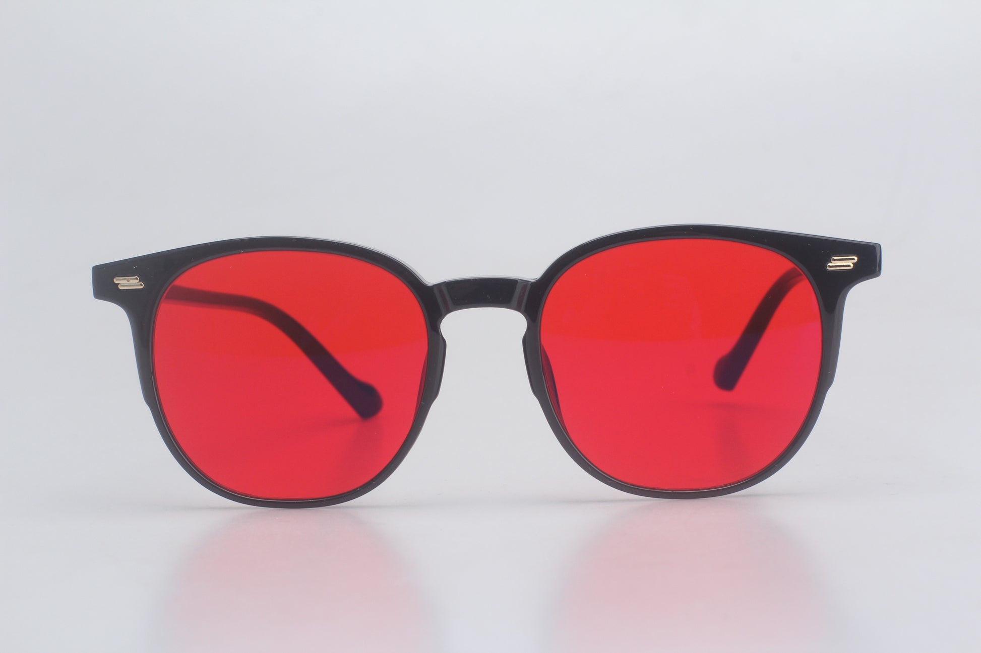 Blue light blocking glasses with red lenses and black frames on a light gray background