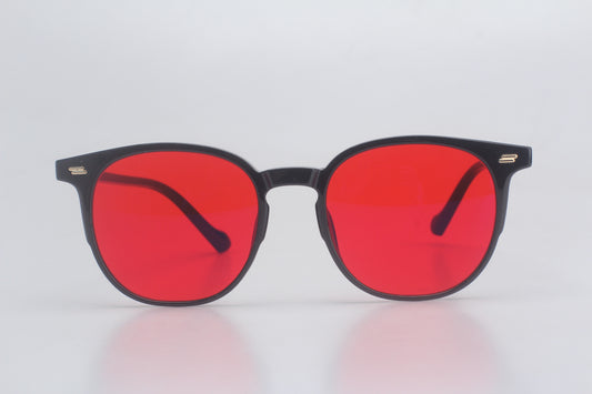 Blue light blocking glasses with red lenses and black frames on a light gray background
