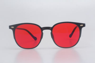 Blue light blocking glasses with red lenses and black frames on a light gray background