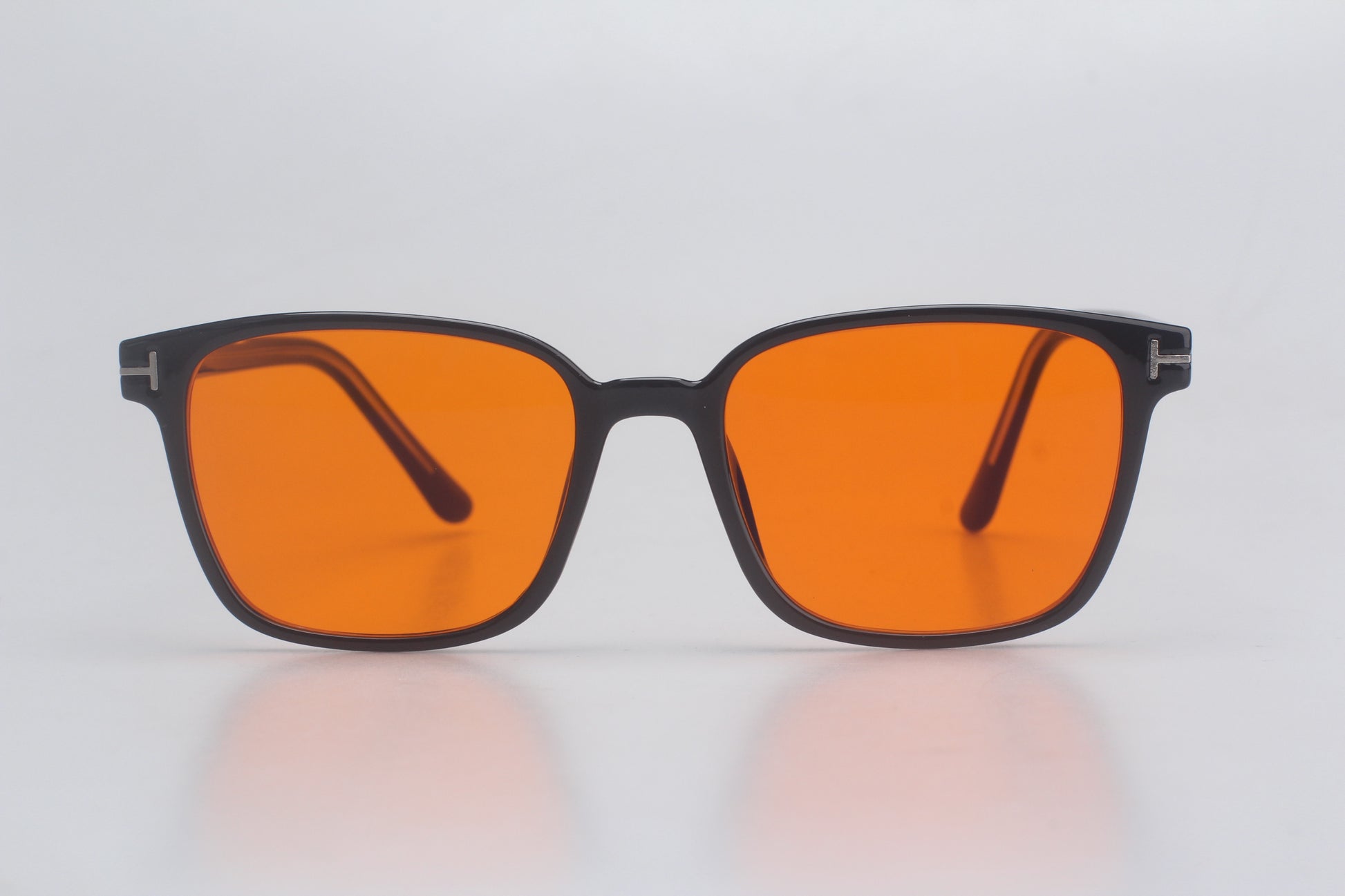 Blue Light blocking glasses with orange lenses and black frames on a light gray background