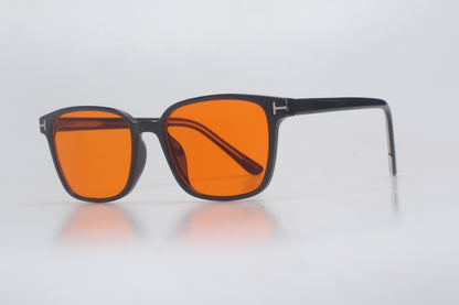 Blue Light blocking glasses with orange lenses and black frames on a light gray background