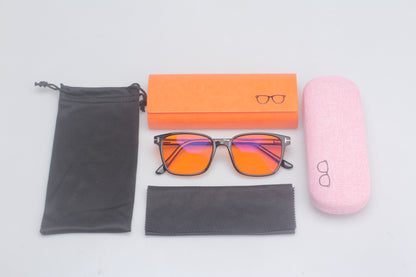 Eyeglasses with orange-tinted lenses, black case, pink case, and cleaning cloth on a light gray background